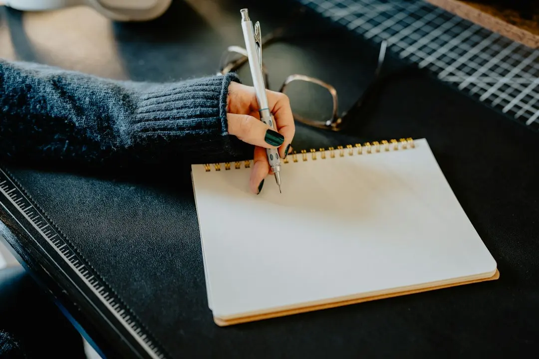 A person writing a checklist in a notebook at a desk, comparing IPTV providers such as Drogon TV